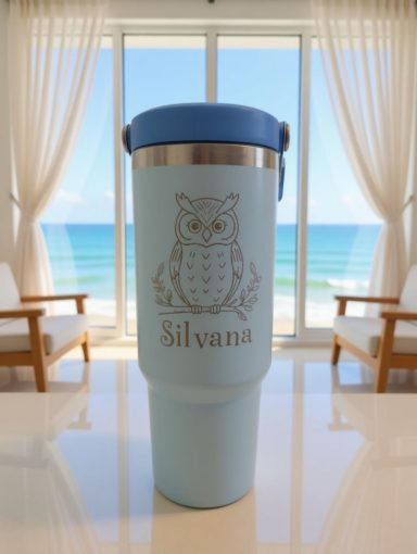 Türkise Thermotasse mit Eule vor einem Fenster mit Meerblick.